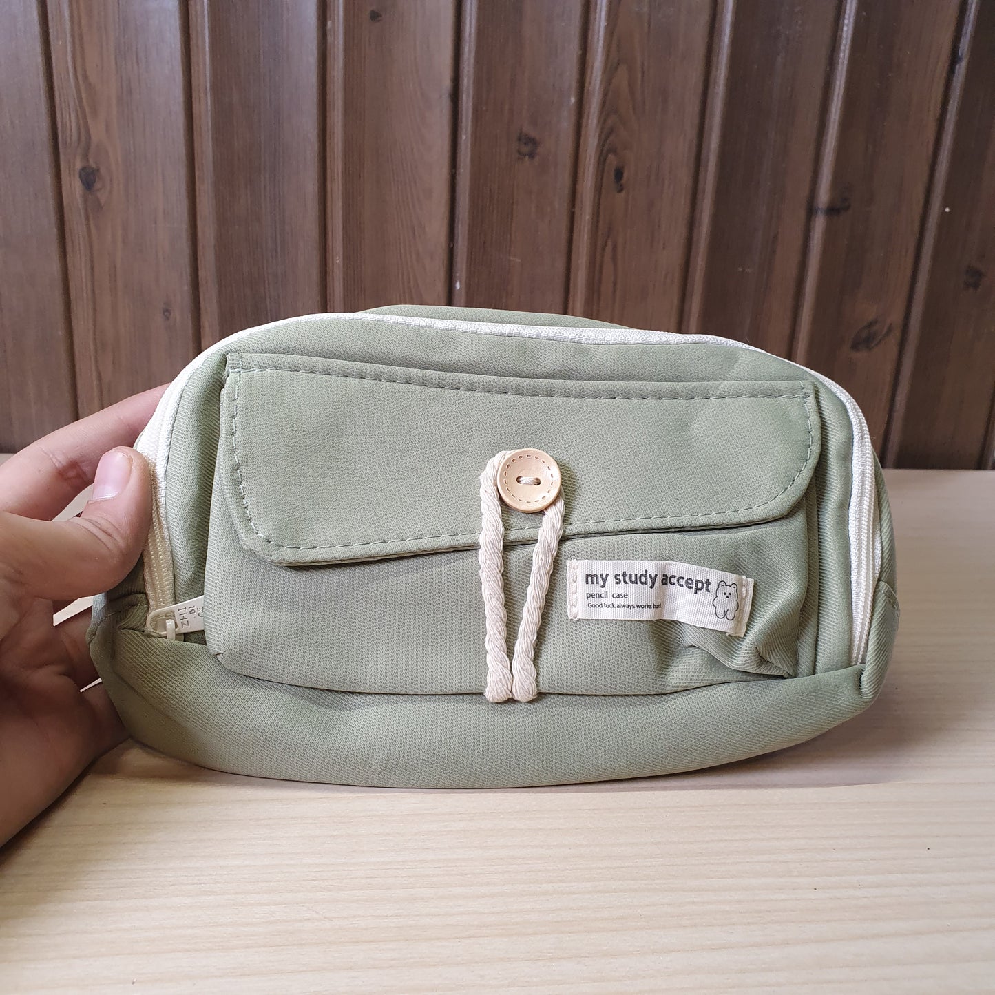 green pencil case features a beige button and white rope accent closure.#8247