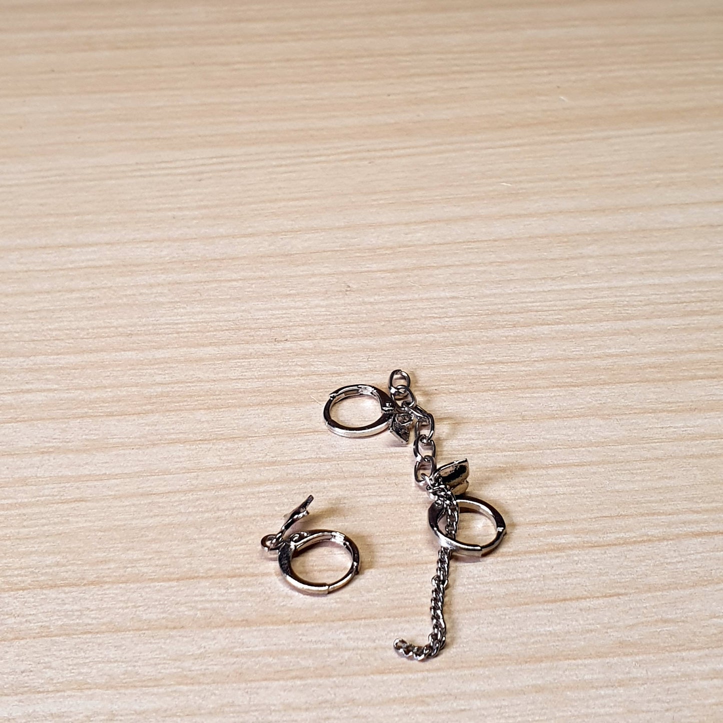 Silver-toned handcuff-style dangle earrings feature small chains and hinged hoop closures.#3492