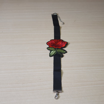 Black ribbon choker necklace features a prominent embroidered red rose patch and an adjustable silver-tone #6873