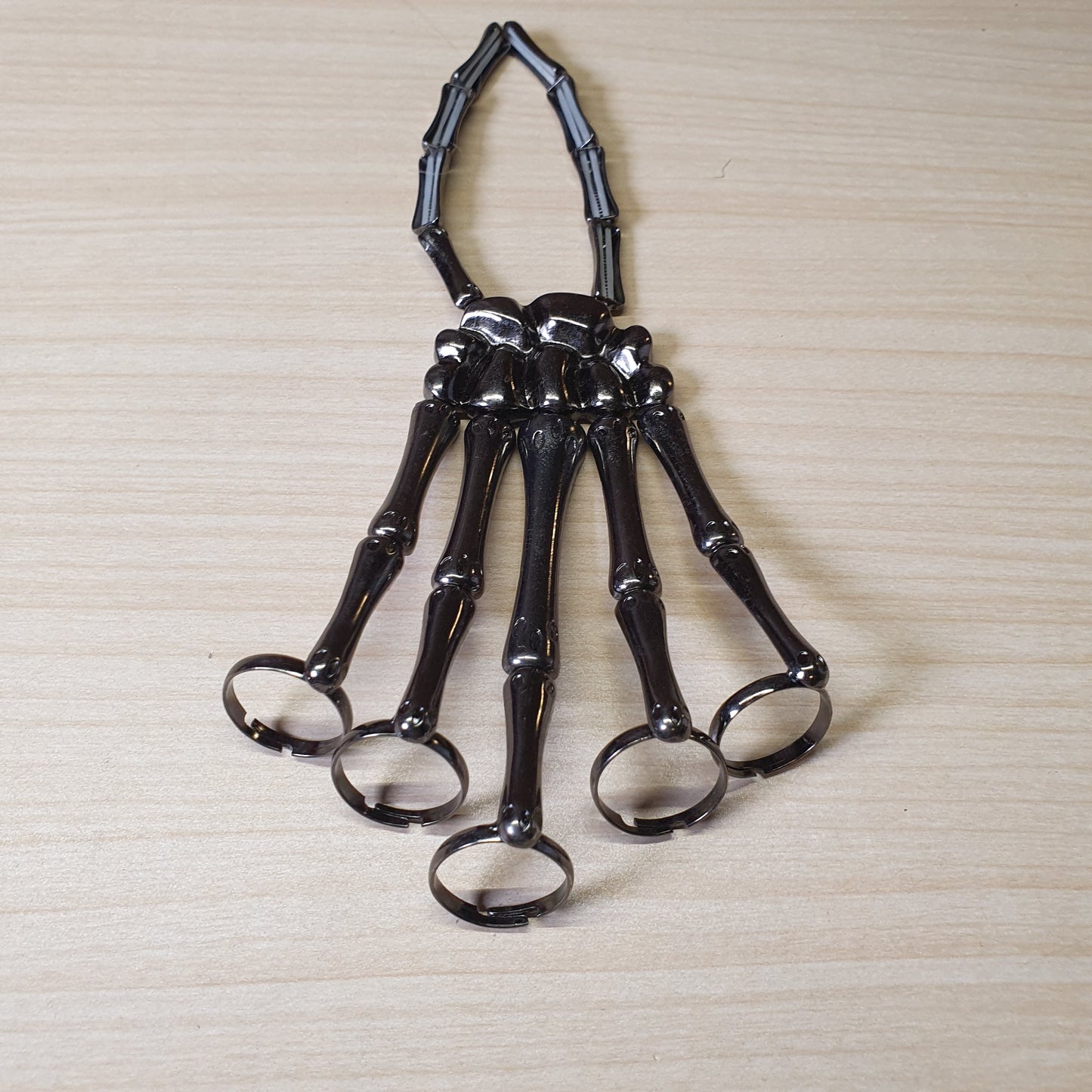 Gothic punk skeleton hand bracelet features five rings attached to a wrist chain. #4543