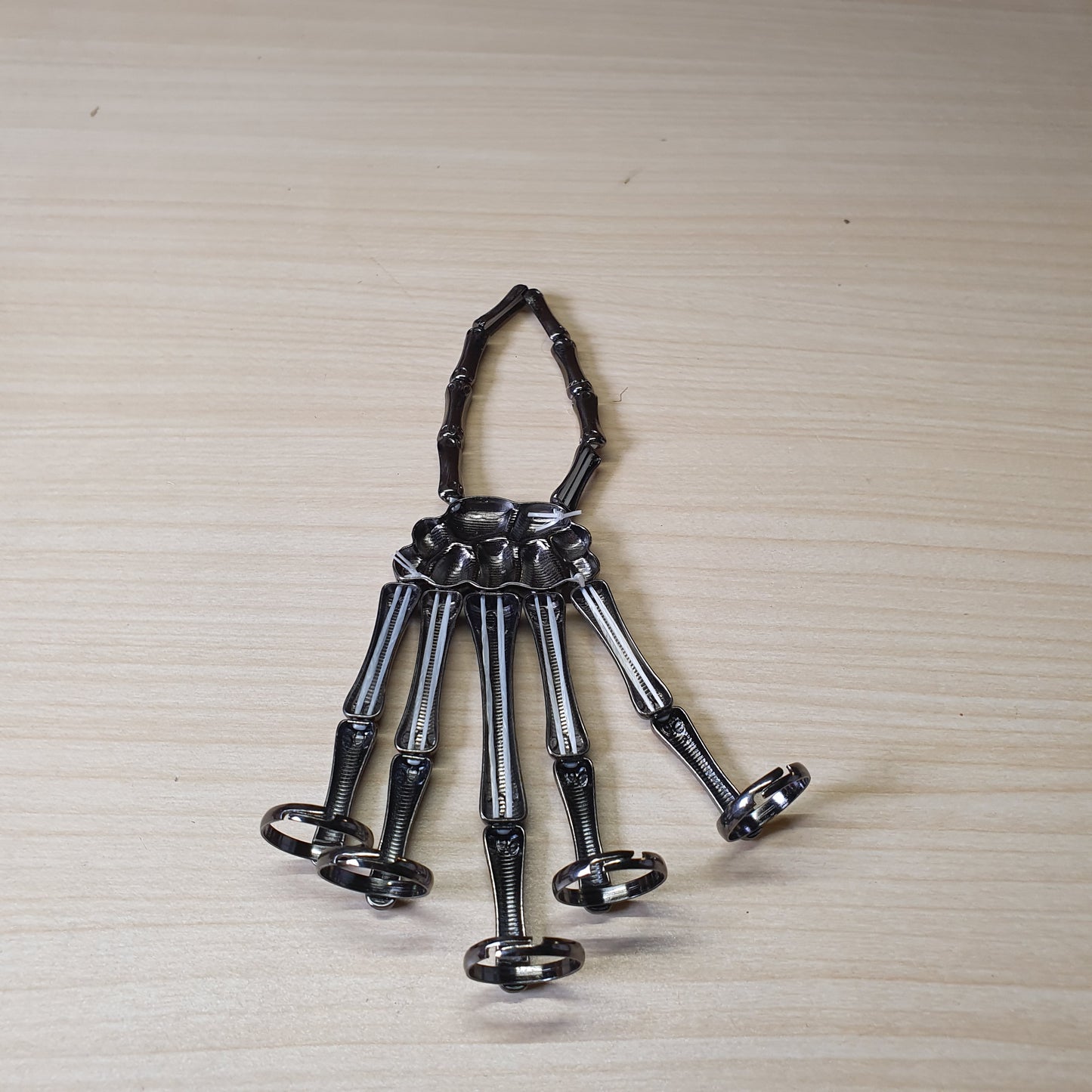 Gothic punk skeleton hand bracelet features five rings attached to a wrist chain. #4543