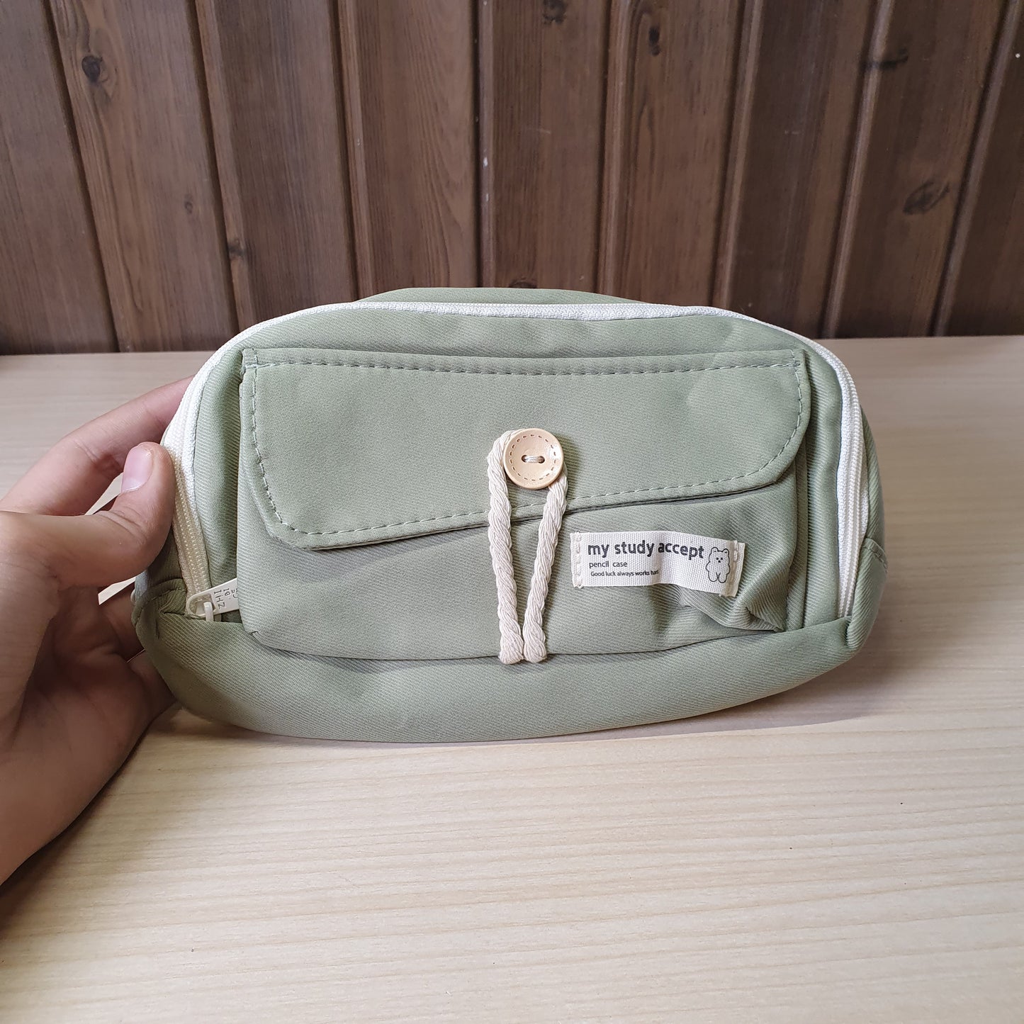 green pencil case features a beige button and white rope accent closure.#8247
