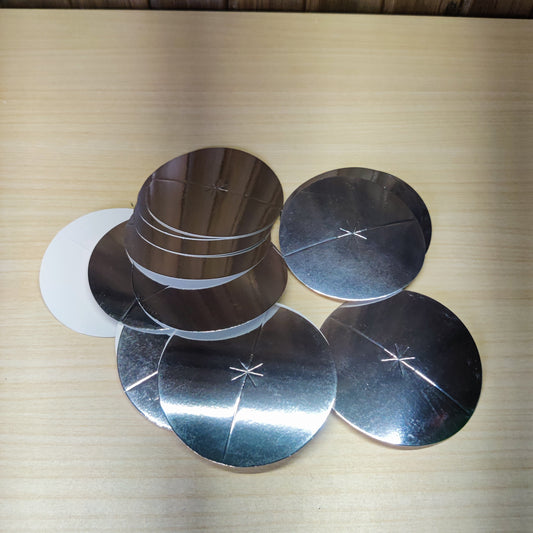 Silver-colored, circular candle drip protector disks made of aluminized paper.#2742